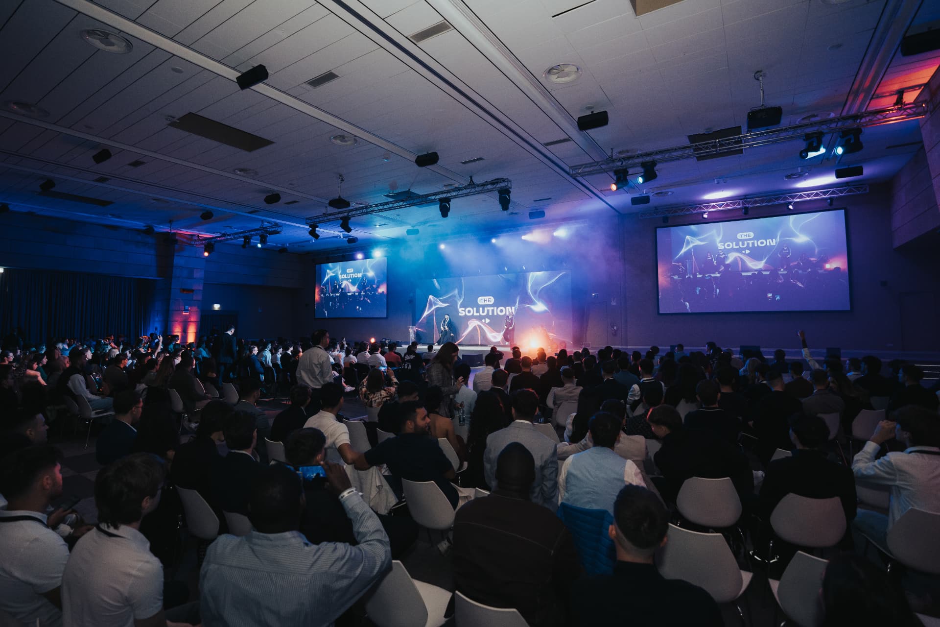 Sala conferenze con palco, schermi laterali e regia luci